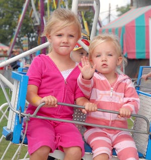 Jasmine Frantz, left, and her sister Jocelyn, waving to her grandma Christine Frantz, take a ride on one of the kiddie rides Labor Day morning on the final day of the Stark County Fair.