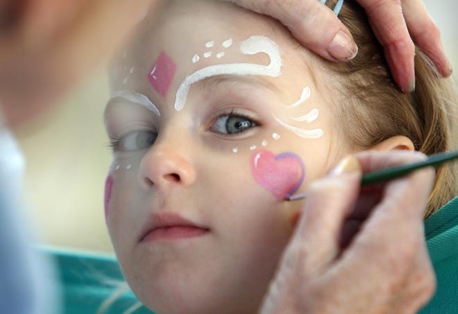Riley Nessralla, 3, of Brockton, gets her face painted by Jane Rowell of Holbrook during a block party on Huchinson Terrace in Whitman on Sunday. The party also served as a fundraiser for the Injured Marine Semper Fi Fund.