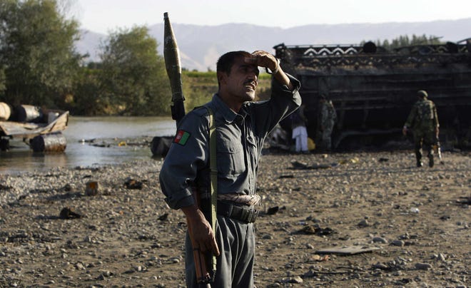 Afghan police inspect the site where American jets bombed fuel tankers hijacked by the Taliban, outside Kunduz.