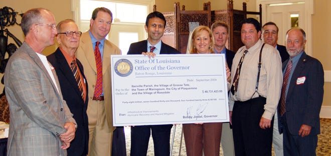FEDERAL WINDFALL...Gov. Bobby Jindal delivers a “check” for nearly $50 million – most of it federal funds for hurricane recovery or protection – to Iberville Parish Officials at the Chamber of Commerce meeting last Thursday at Nottoway Plantation. Joining in the check presentation are, from left, Alderman Randel “Panco” Badeaux and Mayor Lawrence “Football” Badeaux, both of Rosedale; state Sen. Robert Marionneaux; Jindal; state Rep. Karen St. Germain; Iberville Chief Administrative Officer Edward A. “Lucky” Songy Jr., Parish Councilman Mitchel J. Ourso Sr., and Grosse Tete Mayor Michael D. Chauffe Sr.