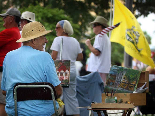 World Wide Paint Out participant Bob Rayunas smiles while he paints as Tea Party protesters surround him, one carrying a flag that reads "Don't Tread on Me," at the Downtown Square on Saturday, September 12, in Ocala, Florida.