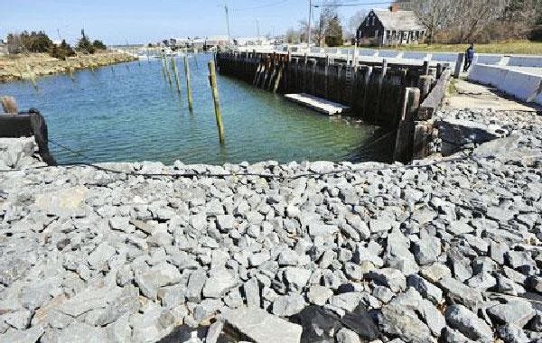 Stones fill an area of the crumbling Barnstable Harbor bulkhead in April. Part of the bulkhead’s retaining wall collapsed last winter.
