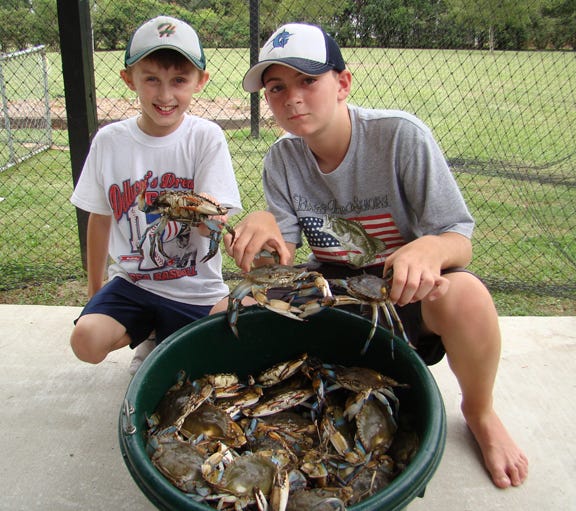 Samuel Bergeron and Trent LeBlanc are seen with a hamper of crabs caught with their fathers in Lake Maurepas recently.