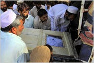Pakistanis loaded into a vehicle the body of a victim of a bombing on Friday in a Shiite village in the North-West Frontier Province.