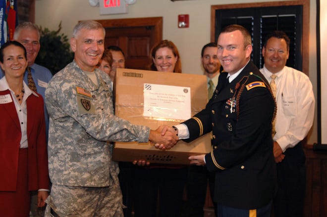 Col. Ed Kertis, commander of the U.S. Army Corps of Engineers Savannah Distric, left, presents Lt. Col. Mike Brophy, an officer with the 3rd Infantry Division\u2019s headquarter command staff with on of the many boxes of toys and school supplies donated by members of the Savannah chapter of the Society of American Military Engineers for children in the Iraqi villages where Brophy will soon be deployed. (John Carrington/Savannah Morning News)
