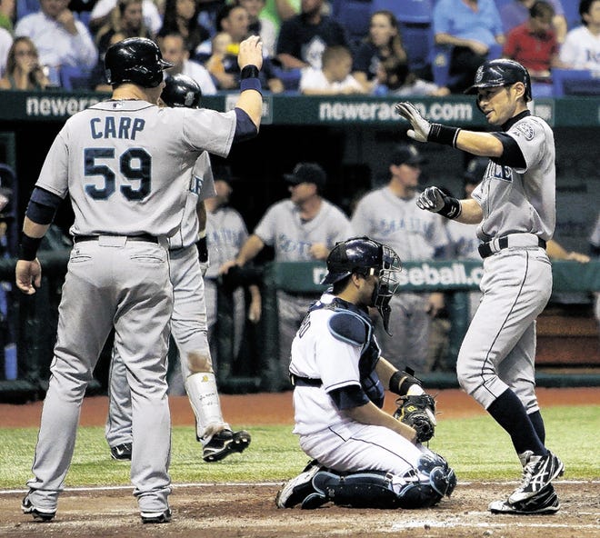 Seattle Mariners' Ichiro Suzuki, right, of Japan, reaches out to high-five teammate Mike Carp after Suzuki hit a fifth-inning, two-run home run off Tampa Bay Rays pitcher Jeff Niemann during a baseball game Tuesday Sept. 22, 2009, in St. Petersburg, Fla. Catching for Tampa Bay is Dioner Navarro.