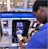 Derrick Brooks, a worker at a Best Buy store in Palo Alto, Calif., looking over an electronic book reader made by Sony.