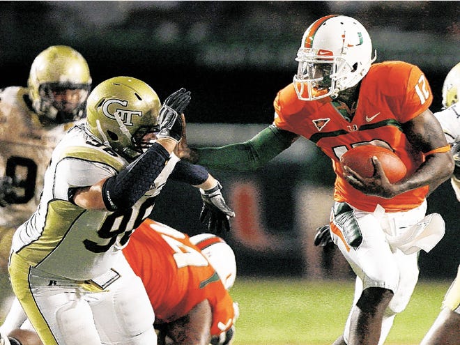 This is a Sept. 17, 2009, file photo showing Miami quarterback Jacory Harris (12), fending off Georgia Tech's Ben Anderson (98), during second quarter of an NCAA college football game, in Miami. Harris is already being talked about as a Heisman Trophy candidate and the stigma of three straight disappointing seasons seems all but gone.