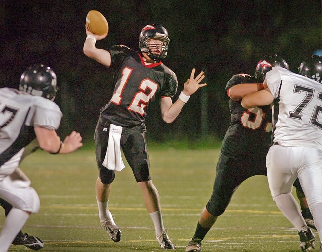 North Quincy quarterback Mike Stanton sets up to pass as the Plymouth South defense closes in.