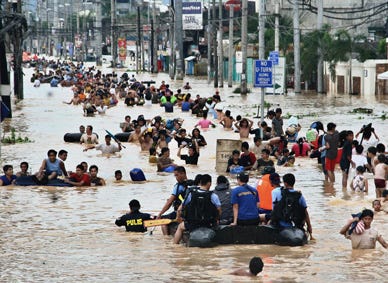 People wade in the chest deep floodwater Sunday, Sept. 27, 2009 in suburban Cainta, east of Manila, Philippines. Rescuers plucked bodies from muddy floodwaters and scrambled to save drenched survivors on rooftops Sunday after a tropical storm tore through the northern Philippines and left 75 people dead or missing in the region's worst flooding in more than four decades.