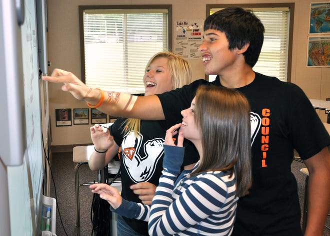 Jessica Johnson (from left), 15; Bryan Amezquita, 14; and Abbey Green, 15, laugh as they play a game on a Smart Board at Harlem High School's Ninth Grade Campus. Even though class was not in session Monday, Sept. 28, 2009, members of the school's student council led a tour through the building as part of a grand opening celebration.