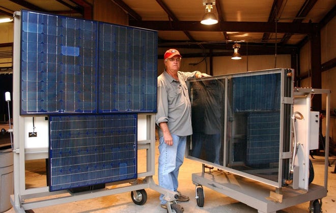 TERRY DICKSON/The Times-UnionJ.J. Johnson stands between photoelectric panels (left) and a solar water heater that could basically heat water free in most homes.
