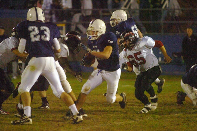 Rockland's Tim Fitzgerald, center, carries the football past North Quincy defender Colin Hayes, right.