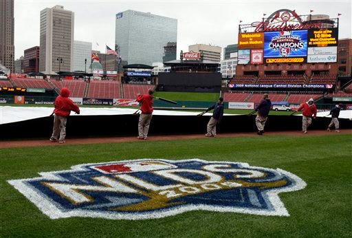 Members of the St. Louis Cardinals grounds crew pull a tarp over the field in Busch Stadium Friday, Oct. 9, 2009, in St. Louis. Heavy rains have forced the cancellation of practice for Game 3 of the National League Division Series baseball game set for Saturday between the St. Louis Cardinals and Los Angeles Dodgers. (AP Photo/Jeff Roberson)