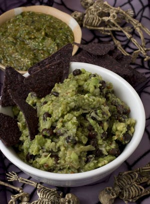 Serve blue corn chips with these two dark, swampy and delicious dips -- Guacamole with Black Beans, foreground, and Tomatillo Salsa Verde -- from "Martha Stewart Halloween Spirited Celebrations." (AP Photo/Larry Crowe)