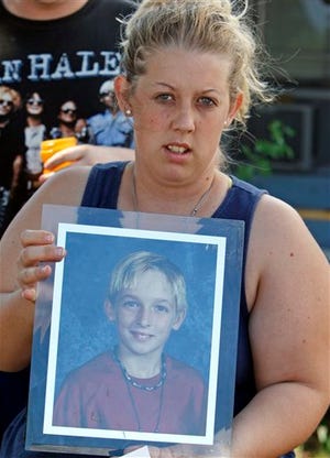 Malissa Durkee holds a framed photo of her brother Michael Brewer as she talks to a reporter in Deerfield Beach, Fla., Wednesday, Oct. 14, 2009. Five teenagers were charged with aggravated battery Tuesday for dousing a 15-year-old with rubbing alcohol and setting him on fire because he stopped someone from stealing his father's bicycle, authorities said. Michael Brewer was hospitalized with burns on more than three-quarters of his body after the attack at a Deerfield Beach apartment complex Monday.