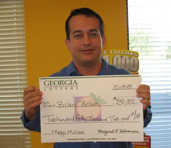 Brian Brown, of Port Wentworth, poses with the $250,000 check after matching five numbers in the recent Mega Millions drawing. (Photo courtesy of the Georgia Lottery Corp.)