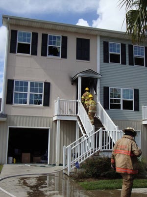 Firefighters shimmy up the stairs to a Thunderbolt town home that caught fire Friday afternoon. Despite their efforts, two dogs died in the blaze. Arek Sarkissian II/Savannah Morning News