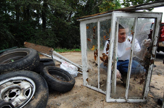 Bryan Templin looks through a broken window pane as he and other volunteers wait for a truck to pick up trash they had removed from a bank of the Augusta Canal. The Community Partners for Clean Waterways put on the Rivers Alive Augusta Canal and Lake Olmstead Cleanup. Volunteers later got a picnic lunch.