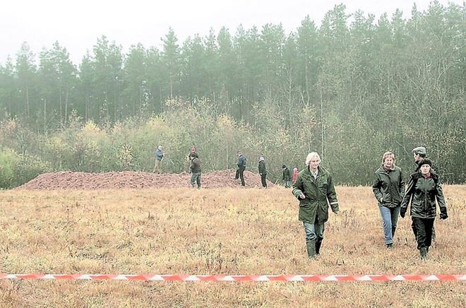 People are seen near a crater, 27 feet wide and 9 feet deep, in the Mazsalaca region, northern Latvia, near the Estonian border, on Monday. A Swedish mobile phone company admitted to the hoax. AP photo