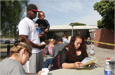 Justine Trevino filled out forms on health requirements for the swine flu vaccine at El Camino College in Compton, Calif., as Charles Booth and their son, Kai, 11 months old, looked on. Charles got the vaccine earlier because he is the caretaker of a toddler.