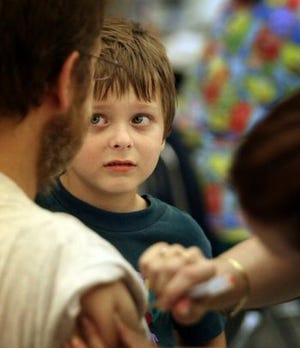 Collin Pierce, 5, cries as Bridgitte Frantz gives his father, Shawn, a shot at an H1N1 vaccination clinic Tuesday at Dunnellon Elementary School. Collin already had received his vaccination, but seemed upset by the sight of his dad getting his. Hundreds lined up for the first vaccine clinic in the county.