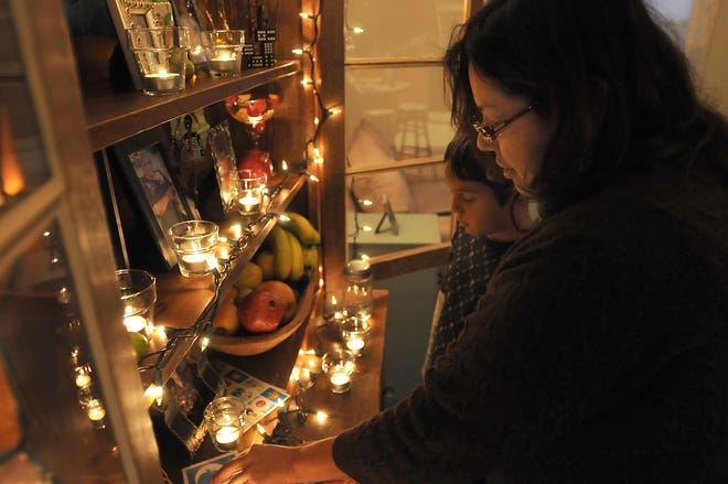 Dennis R.J. Geppert/The Holland Sentinel 
Alonso Rios and his mother Molly Rios adjust their Day of the Dead alter at their home in Fennville.