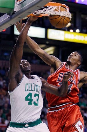 Boston Celtics center Kendrick Perkins, left, dunks as he passes Chicago Bulls forward Tyrus Thomas on a drive to the basket in the first quarter of an NBA basketball game in Boston, Friday, Oct. 30, 2009.
