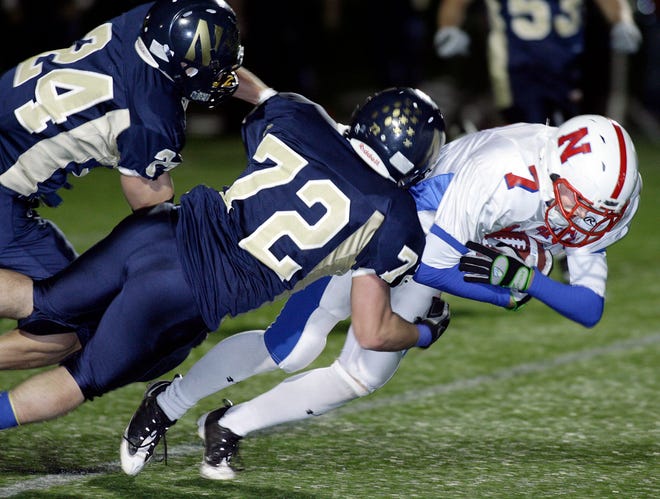 With two defenders on him Natick's #7 Brett Flutie leans in for more yards in Friday night's game against Needham at Needham H.S.