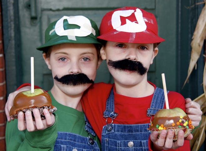 Ericka Kauffman (left), 9, and twin sister Erinna, both of Belvidere, dressed as Luigi and Mario characters, show off the carmel apples they made on Saturday, Oct. 24, 2009, at The Sweetery in Belvidere.