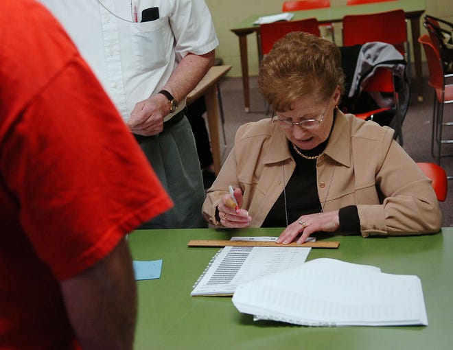 Election Inspector Irene Clague checks in voters at the West Branch Library in Brockton Tuesday.
