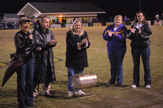 Child Advocacy Services’ Michelle Gallo, at left, announces the winner of the first drawing for the CASA cottage raffle during halftime of St. Amant High School’s game Friday night against Hahnville.