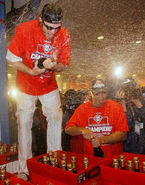 Philadelphia Phillies' Jayson Werth, left, opens a bottle of champagne while celebrating their victory in Game 5 of the National League Championship Series over the Los Angeles Dodgers on Thursday, Oct. 22, 2009, in Philadelphia.
