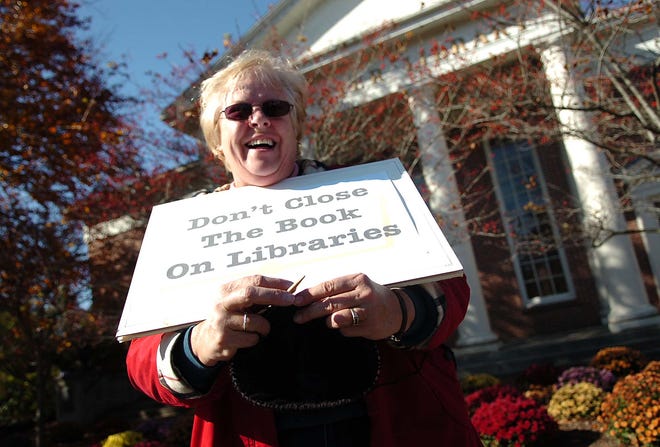 Mary Arnberg knits while holding a sign as she participates in a rally Wednesday in front of the Bridgewater Public Library as part of a statewide effort to stave off further budget cuts.
