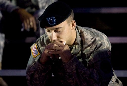 AP Photo/Steven Doll, Killeen Daily Herald   An unidentified soldier says prayers before a candle light vigil Friday, at Hood Stadium on the Fort Hood military post for the victims of Thursday's mass shooting.
