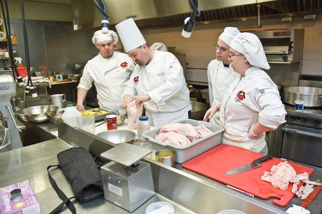 Professor Anthony Giuffre shows culinary arts students how to season a duck for roasting.