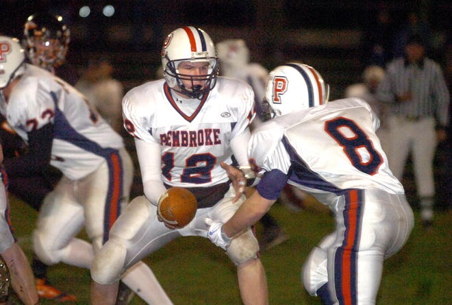 Pembroke quarterback Luke Nagle, left, hands off to running back Benjamin Healey during the Titans' 21-19 win over Middleboro Friday night.
