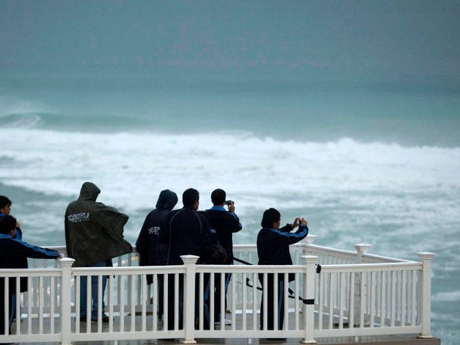 People watch the waves in the resort area of Cancun, Mexico, Sunday, Nov. 8, 2009. Ida has grown into a hurricane for a second time as it moves over the Caribbean.
