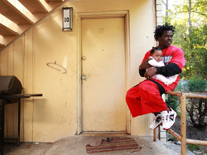 Glenn Springs Manor resident Danny Walker, 32, holds his 4-month-old daughter, Danniya Walker, outside the front door of his apartment Wednesday. The public housing area is closing, and Walker, who's been living there for the last six years, said he's happy about the move because he said crime in the area is too high.