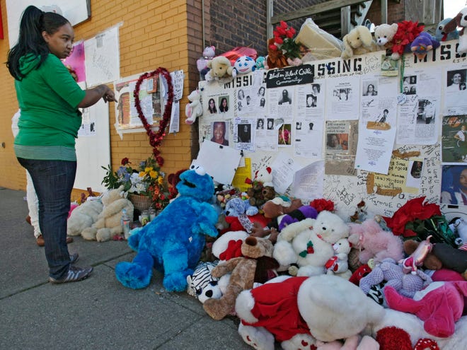 A woman views a memorial across the street from the home of Anthony Sowell on Imperial Ave. in Cleveland Wednesday, Nov. 11, 2009. The remains of 11 bodies were discovered at the house.