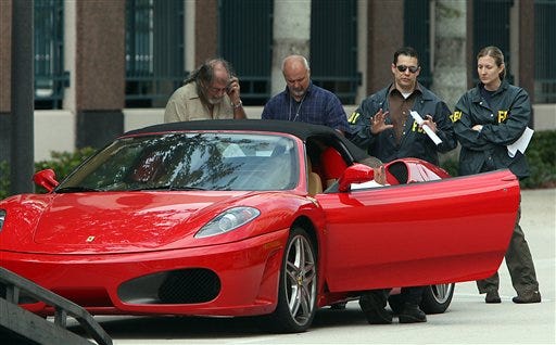 FBI agents watch over a 2006 Ferrari Spider convertible, owned by Scott Rothstein, as it is readied for towing Monday, Nov. 9, 2009 in Fort Lauderdale, Fla. Federal agents were at the ritzy Fort Lauderdale home of Rothstein, a lawyer suspected of orchestrating a multimillion-dollar fraud scheme, seizing assets on Monday.