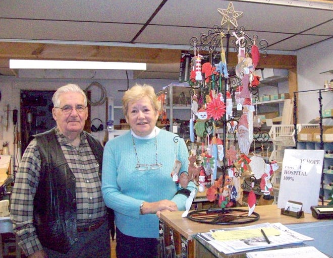 Woodcarvers Loren and Maria Lagoy stand with the Tree of Hope which is full of hand-carved Christmas ornaments ready to sell to benefit the VA Hospital in Bedford.
