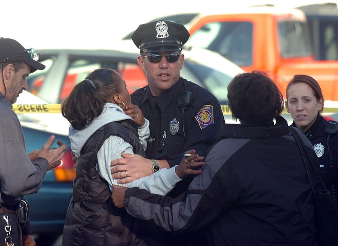 Police comfort two women at the scene of a shooting on North Main Street in Brockton Monday.