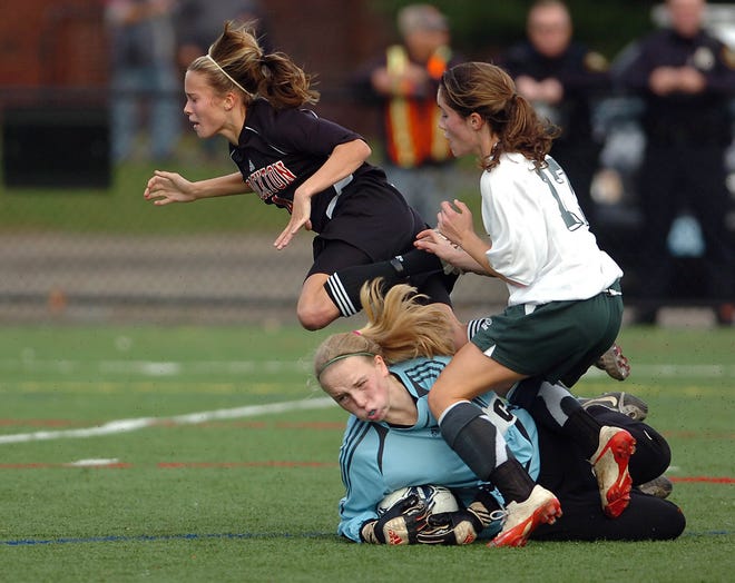 Brockton's Felicia Mulholland and Dartmouth's Kerin Gaydou fall over Dartmouth goalie Amy Wheaton as Brockton girls soccer takes on Dartmouth at Veteran's Memorial Stadium in Quincy Sunday.