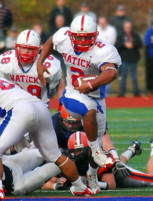 Natick's Scott McCummings busts through the line for a big gain against Walpole on Sunday.