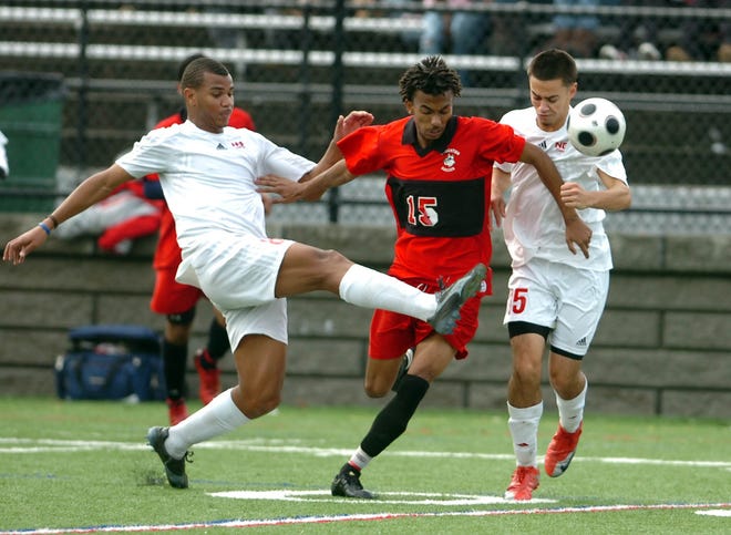 New Bedford's Fernando Baptista and (R) Victor Ferreira fight to get the ball from Brockton's Moises Alves as Brockton boys soccer takes on New Bedford at Veteran's Memorial Stadium in Quincy Sunday.