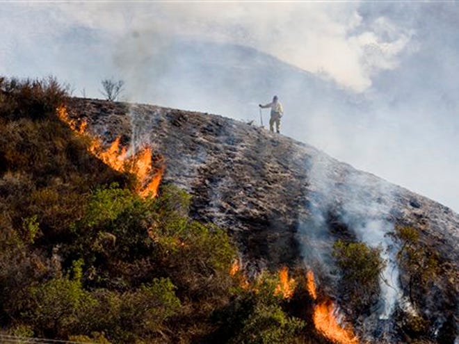An Orange County Fire Authority firefighter stands on a ridge next to the Ortega Highway fire near San Juan Capistrano, Calif., Monday, Nov. 16, 2009.