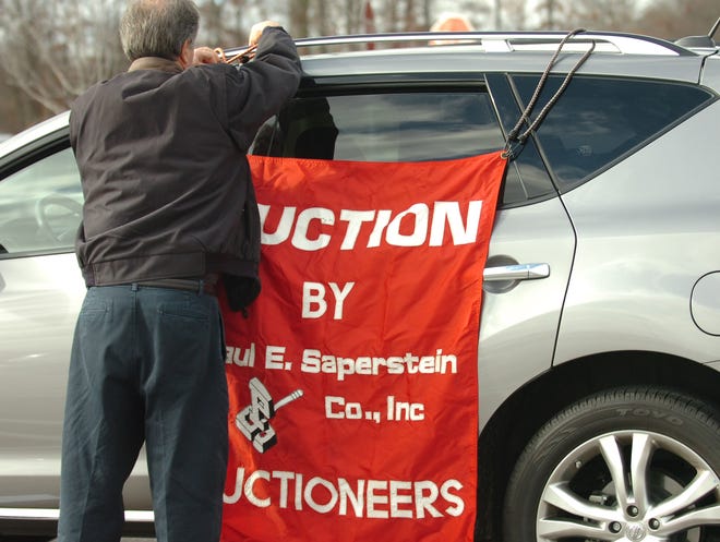 Auctioneer Jeff Mann removes a sign from his car announcing the location of the auction for the Westgate Mall.