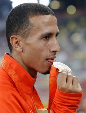 In this Wednesday, Aug. 20, 2008 file photo, Men's 1,500-meter gold medalist Rashid Ramzi of Bahrain licks his medal during the awarding ceremony in the National Stadium at the Beijing 2008 Olympics, China. Rashid Ramzi has been stripped of his 1,500-meter Olympic gold medal for doping, officials with knowledge of the decision told The Associated Press on Wednesday, Nov. 18, 2009. (AP Photo/Petr David Josek, File)