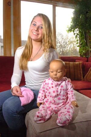 Jeni Kailher, 15, of Whitman, a student at Whitman-Hanson Regional High School sits with a computer doll that shows students whit it's like to have a baby.